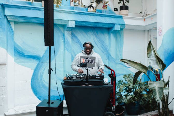 DJ playing a set in front of the blue mural in the Stem & Vine courtyard, Baltimore